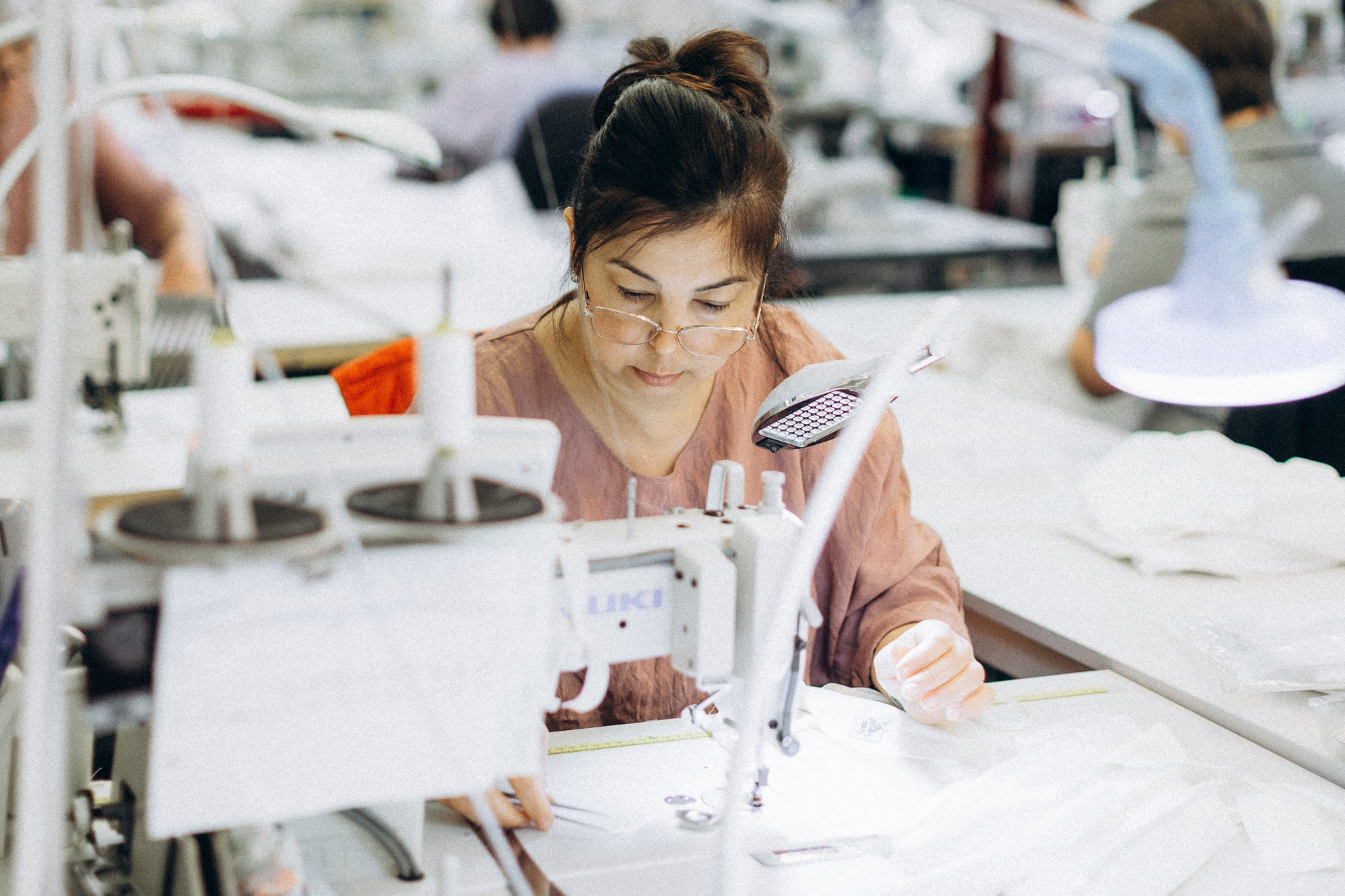 Machinist sewing white fabric at an industrial sewing machine at CMT Studio London