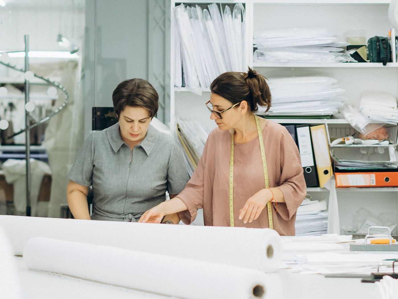 Two studio team members reviewing fabric rolls at the cutting table
