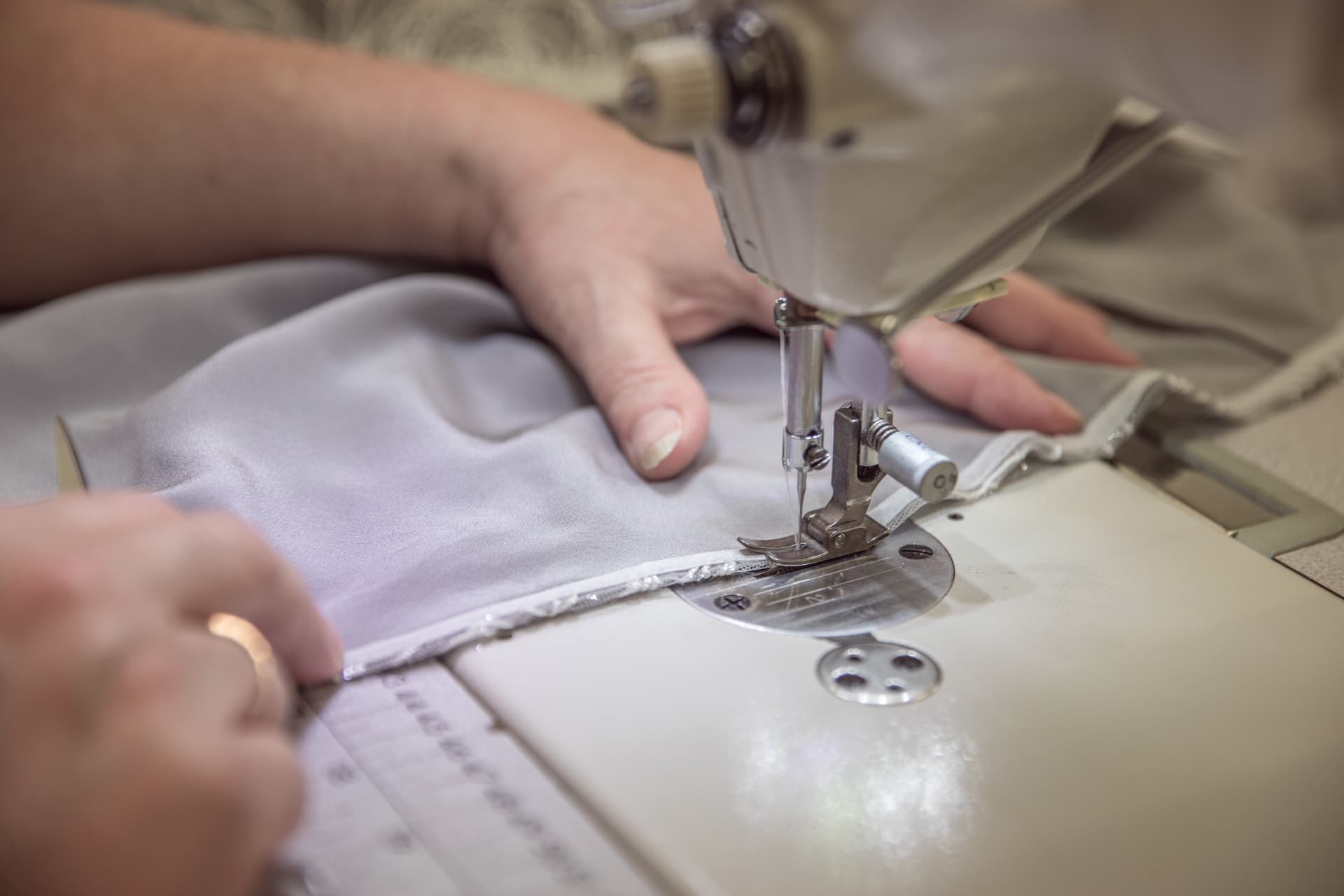 A machinist sewing a silk panel on an industrial machine in the London studio