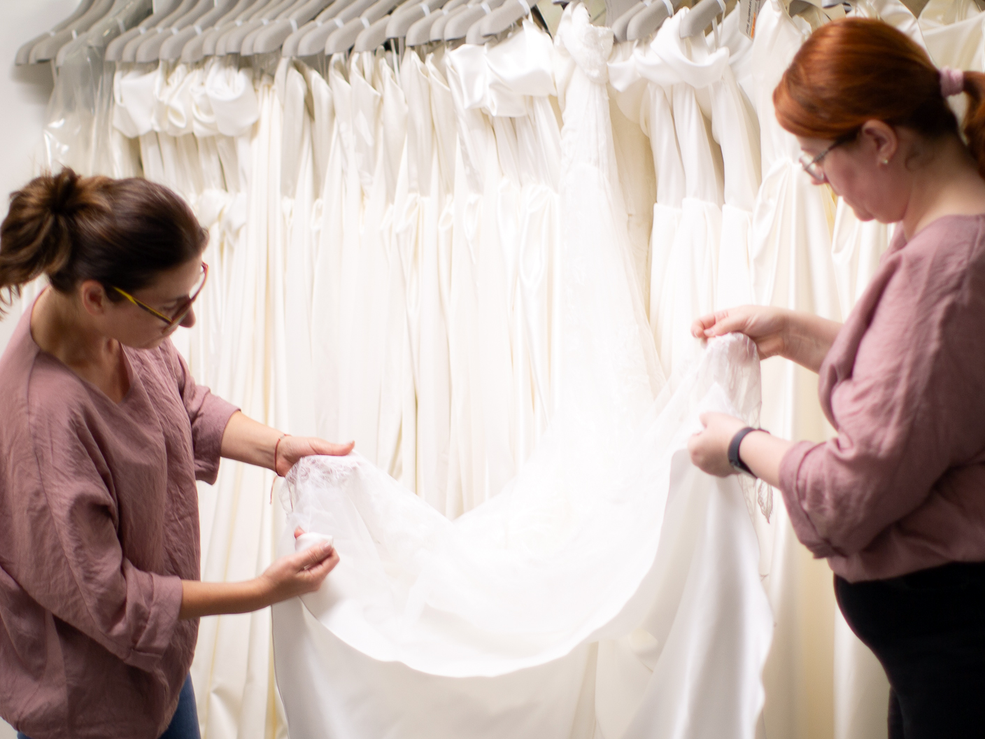 Two women examining a white bridal gown in a studio at CMT Studio London