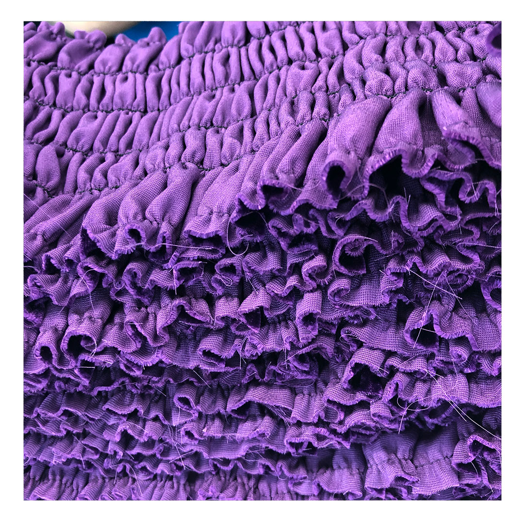 Close-up of deep purple smocked and ruffled fabric, showing the handwork possible in small-run CMT production