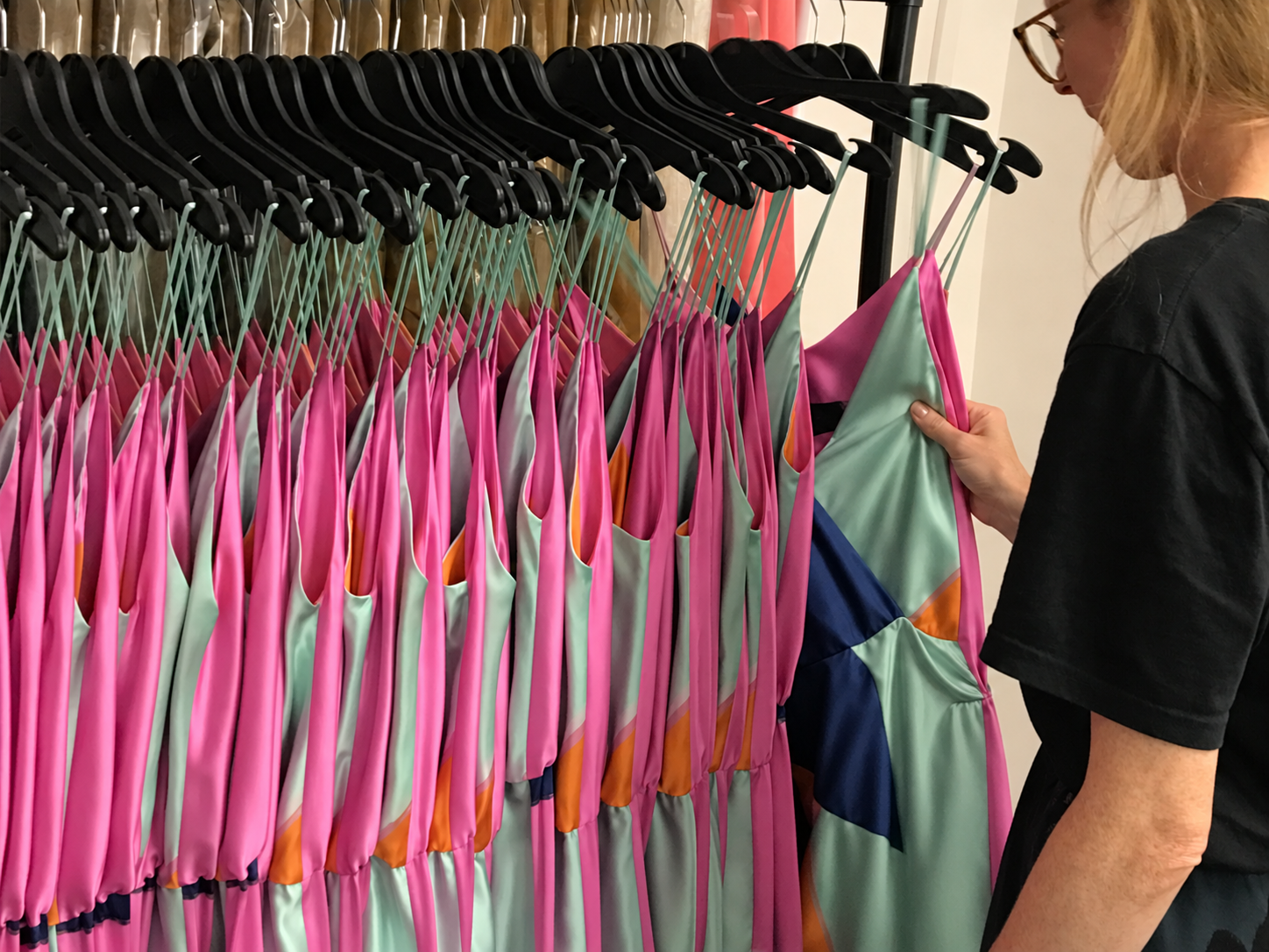 Rows of bright pink garments on hangers being inspected at CMT Studio London