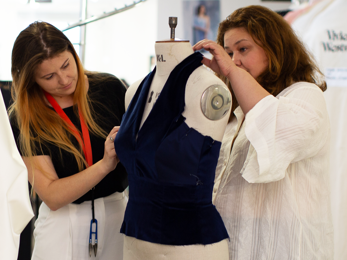 Two women pinning a navy bodice onto a dress form at CMT Studio London