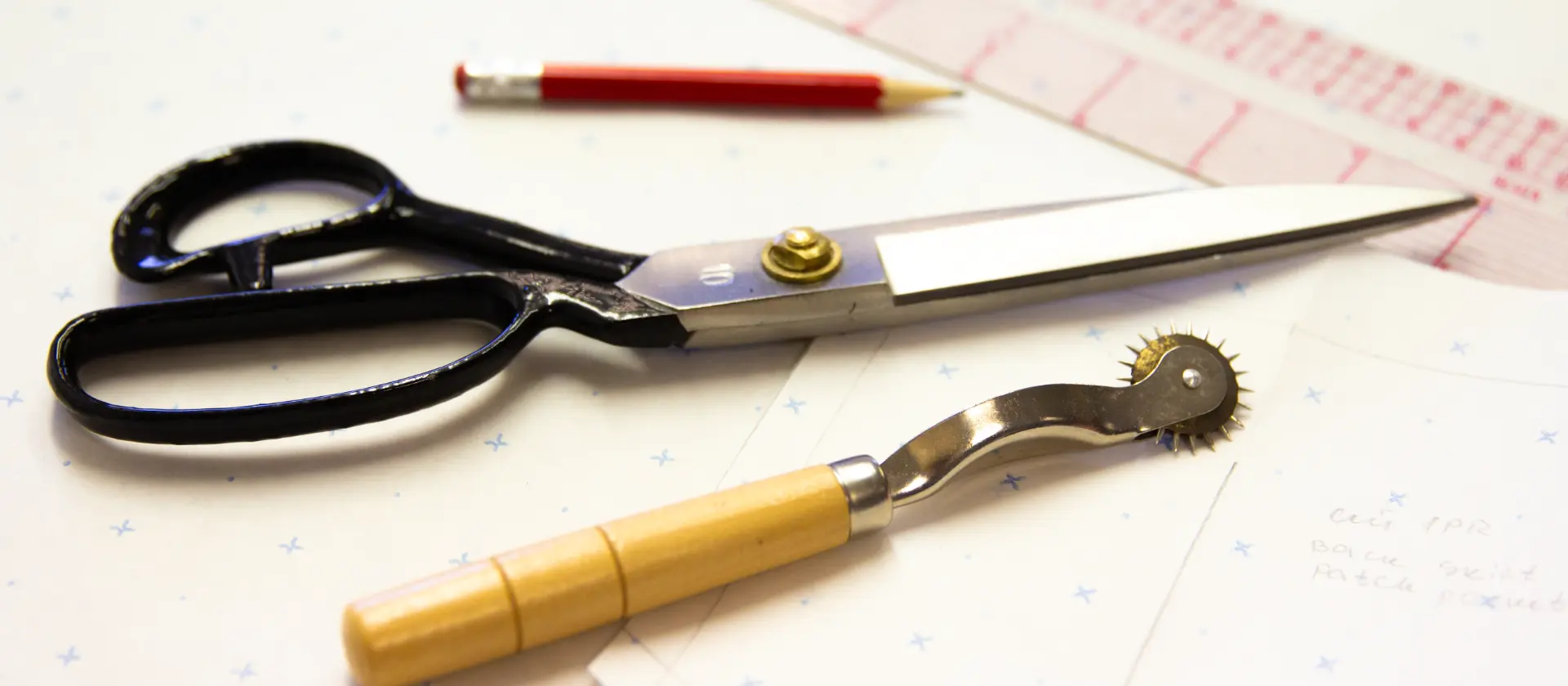 Tailor’s shears, ruler, pencil and tracing wheel on pattern paper at CMT Studio London