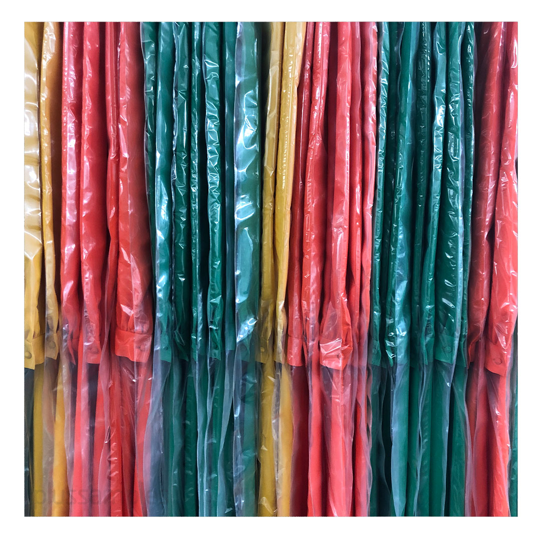 Mass-produced garments in yellow, red and green hanging individually bagged on a rack, illustrating the volume factories need to make a run worthwhile